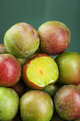 Fresh Ripe Plums with Water Droplets - Red and Green Varieties with Cut Half Showing Yellow Flesh