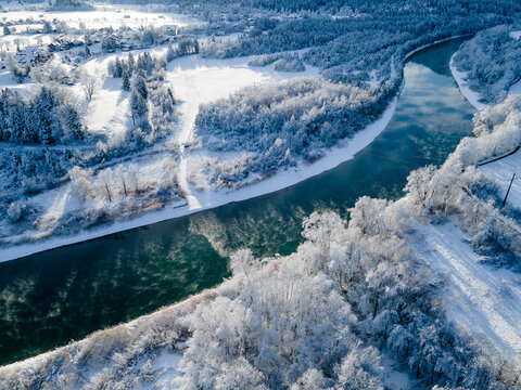 Aerial view of a meandering river cutting through a snow-laden forest, the white trees contrasting with the turquoise water, FÃ¼ssen, Bavaria, Germany. - Powered by Adobe