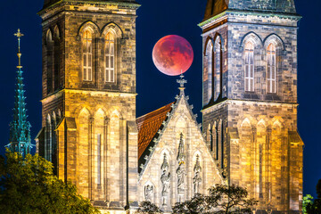 The full Blood Moon during lunar eclipse in between towers of the Vysehrad basilica the UNESCO site in Prague.