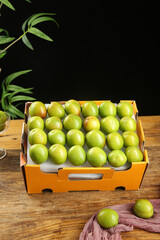 Fresh Green Plums in Orange Box on Wooden Table - Healthy Organic Fruit Display
