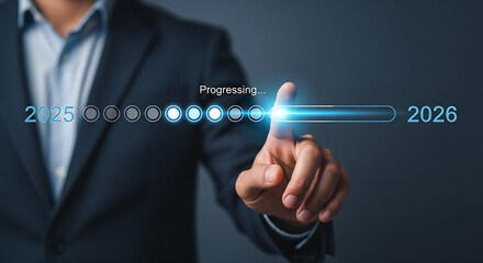 A person in a suit pointing at a progress bar moving from the year 2025 to the year 2026 on a screen