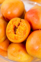 Fresh Ripe Apricots in Glass Bowl with Cut Half Showing Seed and Juicy Orange Flesh