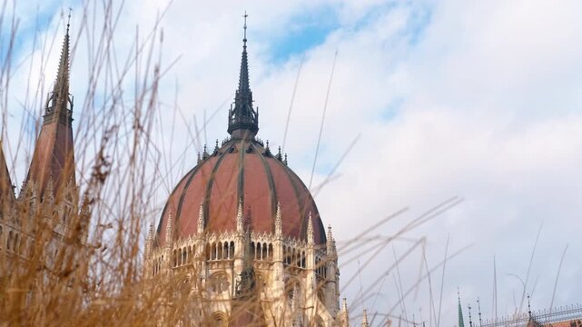 Hungarian parliament building dome rising above dry grass in budapest. Ornate dome of hungarian parliament building rises majestically above dry, golden grass, showcasing intricate architectural