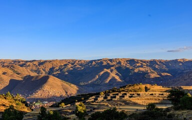 A stunning view of the Saqsaywaman ruins with the Andes mountains under a clear blue sky.