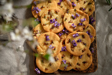 Nut Cookies with edible flowers. Viola, top view, wooden background