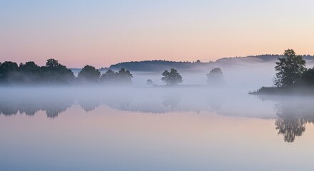 Fototapeta premium Misty Sunrise over a Still Lake, Silhouetted Trees Reflected