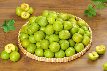 Fresh Green Plums in Wicker Basket on Wooden Table with Mint Leaves