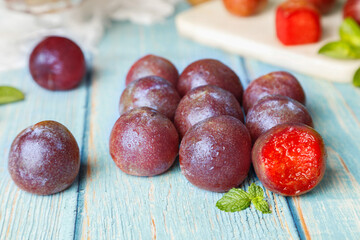 Fresh Red Sanhua Plums with Red Flesh on Rustic Wood Background