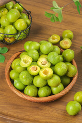 Fresh Green Plums with Pits in Wooden Bowl on Rustic Wood Table