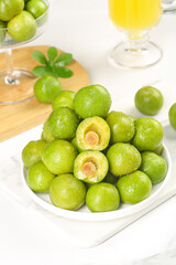 Fresh Green Sichuan Plums in White Bowl on Wood Display - Traditional Chinese Fruit