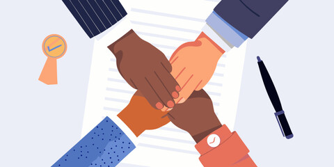 Diverse hands stacked together in unity over documents symbolizing teamwork and agreement