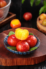 Fresh Red Plums from Guangdong China with Orange Flesh in Ceramic Bowl on Wooden Cutting Board