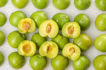 Fresh Sichuan Plums Halved Showing Golden Flesh on White Wood Background