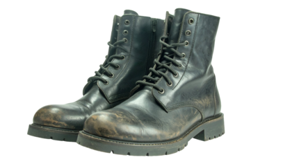 Black leather combat boots pair with chunky soles and worn military style laces on isolated background