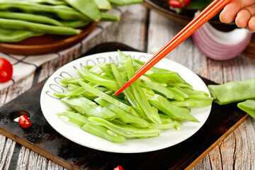 Fresh Green Snap Pea Pods with Red Chopsticks - Healthy Asian Vegetable Dish on Rustic Wooden Table