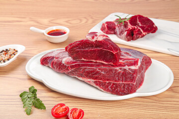 Fresh Raw Beef Steaks on White Plate with Herbs and Seasoning Ready for Cooking