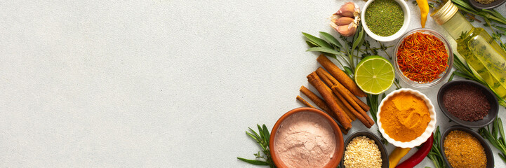 A wide selection of cooking spices and herbs on a gray background, perfect for adding depth to any dish, top view and copy space, banner