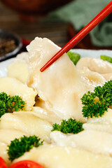 Fresh Steamed Chicken Dumplings with Red Chopsticks and Parsley Garnish on White Plate