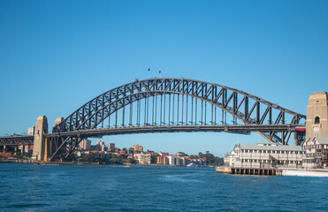 Sydney Harbour Bridge with sailing boats and waterfront houses on a sunny day