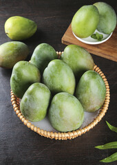 Fresh Green Mangoes in Wicker Basket on Dark Wood Background - Tropical Fruit Still Life