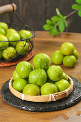 Fresh Green Szechuan Plums in Bamboo Basket on Wooden Table - Crisp Natural Fruit Display