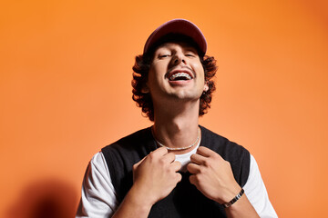 Stylish young man showcasing his fashion and confidence against a vibrant orange backdrop