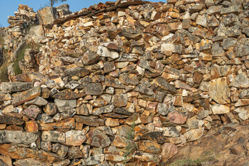 Irregular stone wall in ochre and gray tones, with pronounced joints that highlight the wild and organic texture of the natural rock