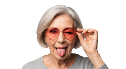 Playful senior woman winks and sticks tongue out wearing heart sunglasses.