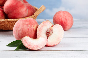Fresh Picked Peaches Display with Sliced Fruit in Wicker Basket on White Wood Background