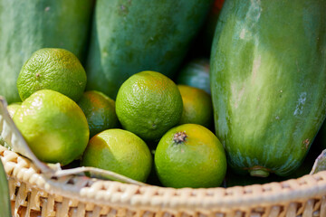 green limes and papaya in basket at market