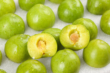 Fresh Green Plums Cut in Half Showing Yellow Flesh and Pit - Healthy Stone Fruit Display