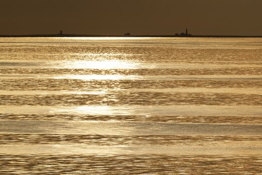 Lighthouses on the horizon, sunbeams are reflected on the sea surface, small waves, Gotland, Baltic Sea