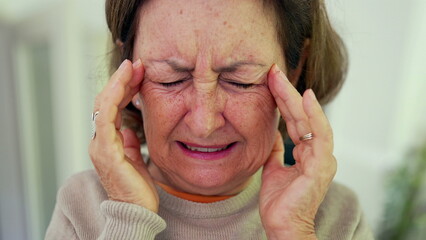 Mature woman experiencing severe headache, squeezing eyes shut, and holding head with both hands, displaying visible discomfort. Wrinkles and facial expression, emotional pain-SD 480p