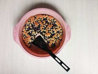 Baked berry pie in pink silicone baking pan. Cut off piece of pie. Top view.