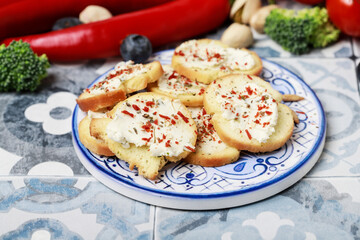 Miniature snacks consisting of crispbread with cottage cheese generously sprinkled with spices. Around it vegetables and fruits.