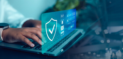 Person Using Laptop with Digital Shield Icon Overlay for Cyber Security and Data Protection