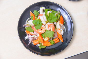 A vibrant and colorful spicy mixed seafood salad featuring fresh shrimp, squid, clab stick and herb on the white background.