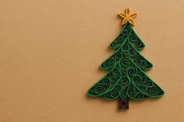 Quilled paper christmas tree with green spirals and yellow star sits on kraft paper background with wide copy space, minimal flat lay style for cards, festive holiday greeting atmosphere