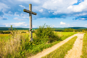 Old Christian cross on side of rural road in farming land on sunny summer day, Roztocze National...