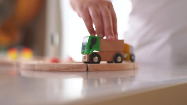 Children play with a toy train in kindergarten. Child childhood fun concept. Train with toy is traveling along railway. Children play with toys and trains on the railway kindergarten in lifestyle.