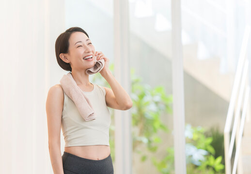 運動してかいた汗をタオルで拭う日本人ミドル女性。