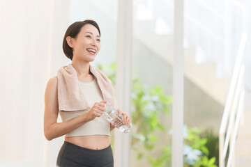トレーニング中に水分補給する日本人ミドル女性。