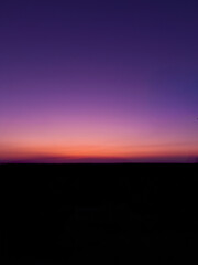A purple sky with a purple and orange horizon and a purple cloud