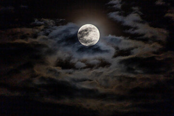 Full moon in the night sky with dark clouds, 