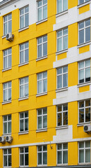 Fototapeta premium Yellow and white building facade with windows and air conditioners