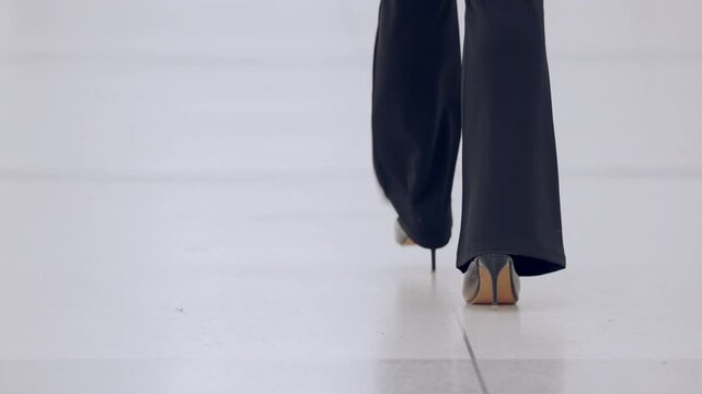 Professional businesswoman in slacks and heels walking confidently, emphasizing progress, independence, and workplace presence.