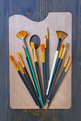 Obraz premium Art palette and various types of artistic paint brushes on dark rustic table