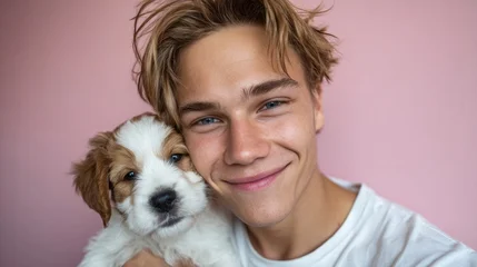 Fotobehang Dierenarts A young man with endearing smile cradles a playful puppy against a soft pink backdrop, radiating warmth and affection.  © DARPANA