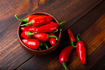 Spicy Organic red hot chili peppers in a wooden bowl, wooden background