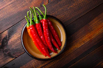 Gardinen Chilischoten Spicy Organic red hot chili peppers in a bowl, wooden background, top view  © Kseniya
